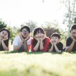 Three children and parents making faces while lying in the grass