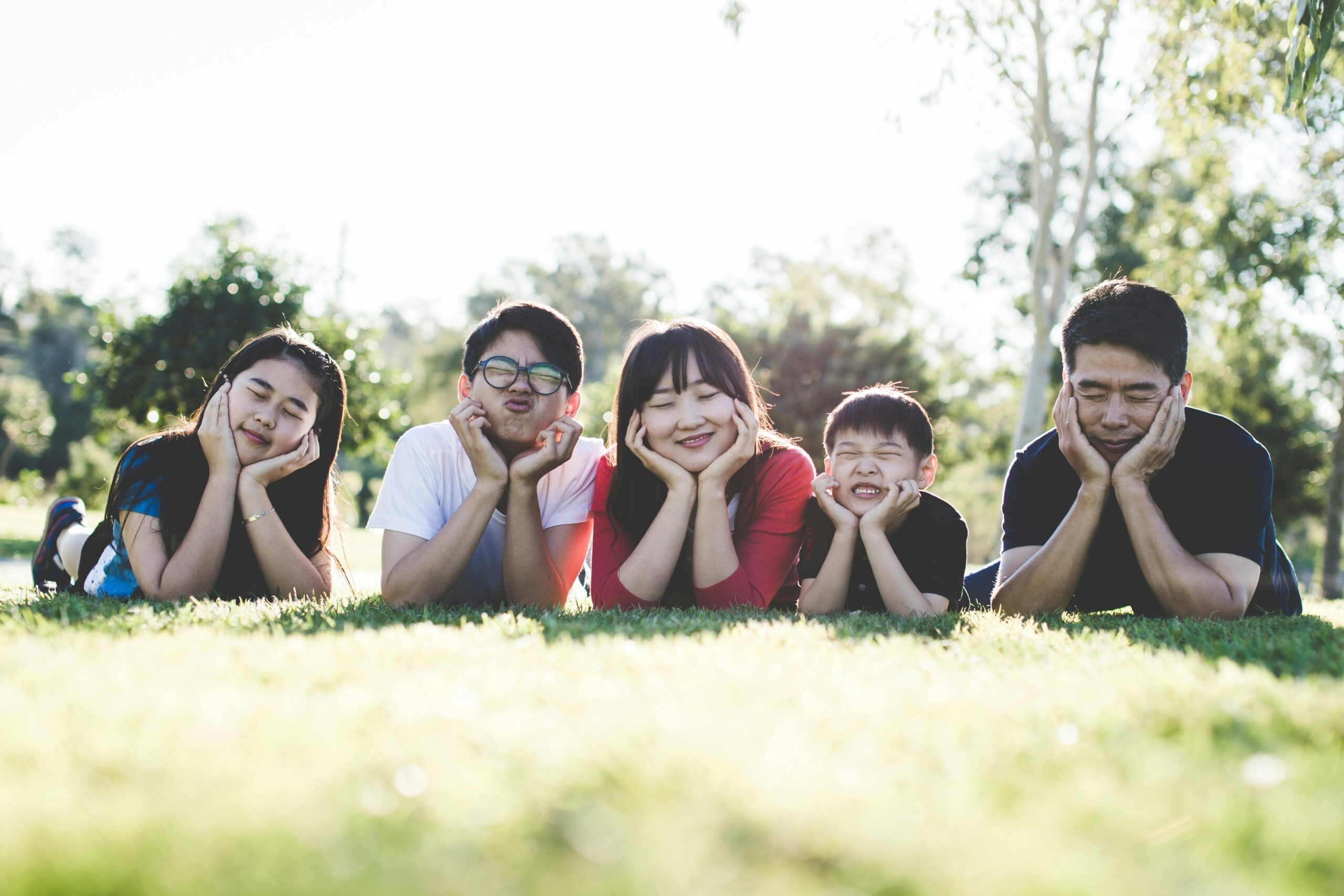 Three children and parents making faces while lying in the grass